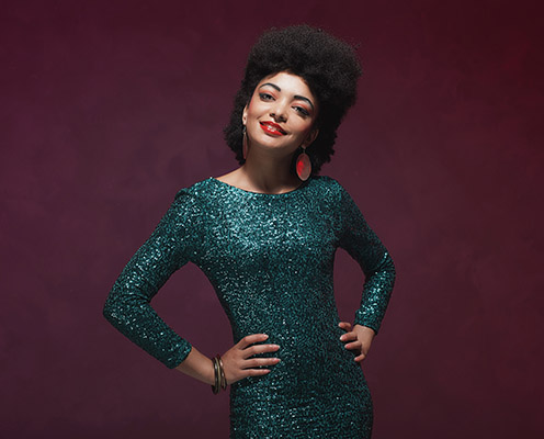 Stylish African American Woman in elegant green dress against maroon